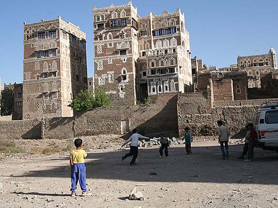 22 Children playing soccer in vacant lot